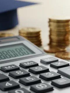 Calculator with coins and graduation cap, symbolizing student loan interest rates and financial planning.