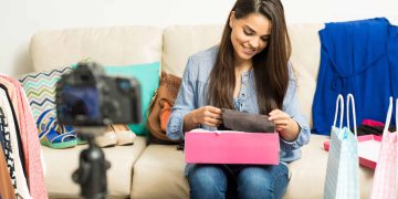 cute-young-female-fashion-blogger-looking-some-new-shoes-while-doing-video-home-scaled